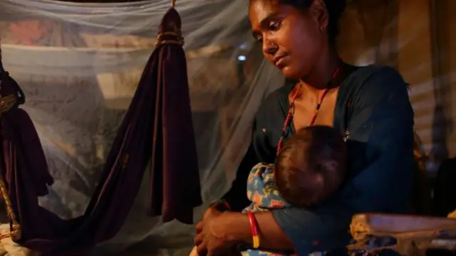 नवजात शिशुलाई स्तनपान गराइरहेकी महिला