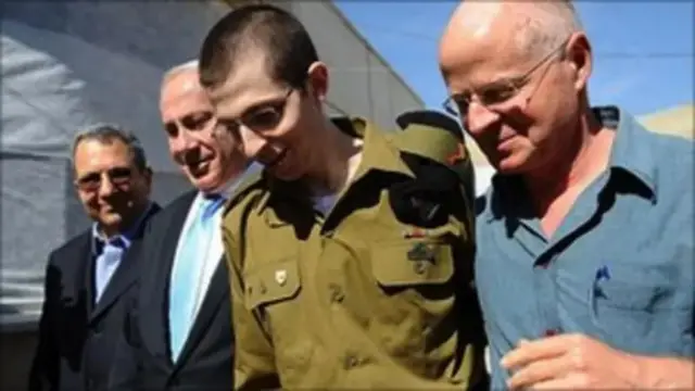Mladić u zelenoj uniformi sa trojicom starijih muškaraca