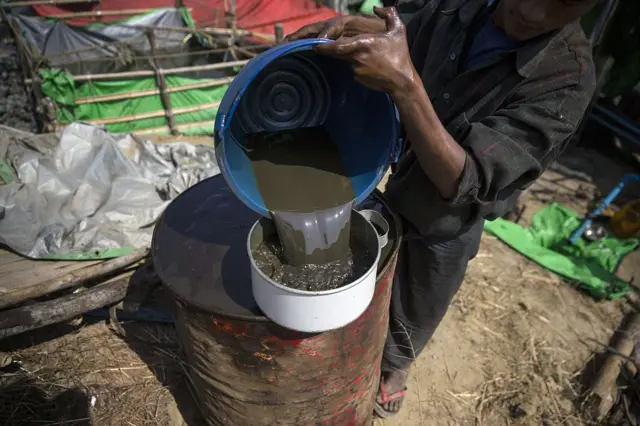 ပဲခူးတိုင်းအတွင်းက ရေနံမှော် က လုပ်သားတစ်ဦး ရေနံစိမ်းလောင်းထည့်နေပုံ (ပုံဟောင်း) 