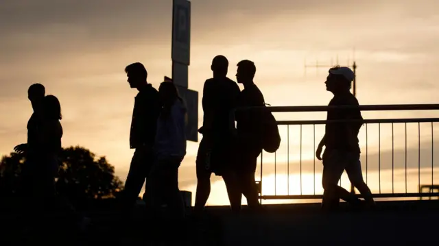 Ludzie przechodzą przez most Świętokrzyski o zachodzie słońca w Warszawie