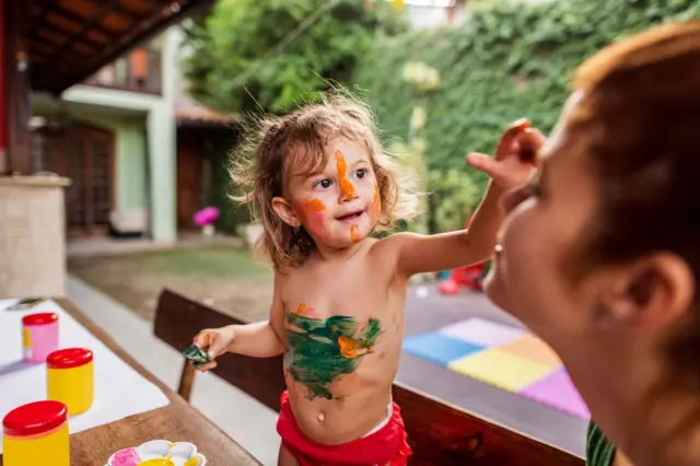 Criança brincandoregras do sportingbetpintar corpo dela e rosto da mãe