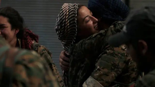 Syria Democratic Forces (SDF) female fighters embrace each other in the city of Manbij