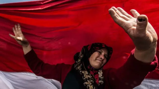 An Egyptian woman dances before a large national flag in Cairo's northern suburb of Shubra al-Khaymah on the second day of voting in the 2018 presidential elections on 27 March.
