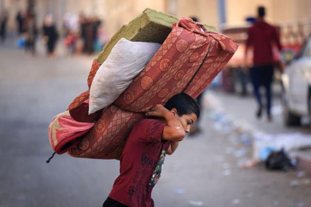 صبي فلسطيني يحمل أمتعته بحثاً عن منطقة أكثر أمانا في مدينة غزة بعد الغارات الجوية الإسرائيلية