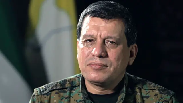 "ژنرال مظلوم عبدی - او لباس نظامی به تن دارد و موی کوتاه تیره دارد."