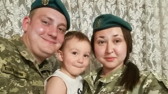 Чоловік і жінка у військовій формі в беретах морпіхів із маленьким хлопчиком 