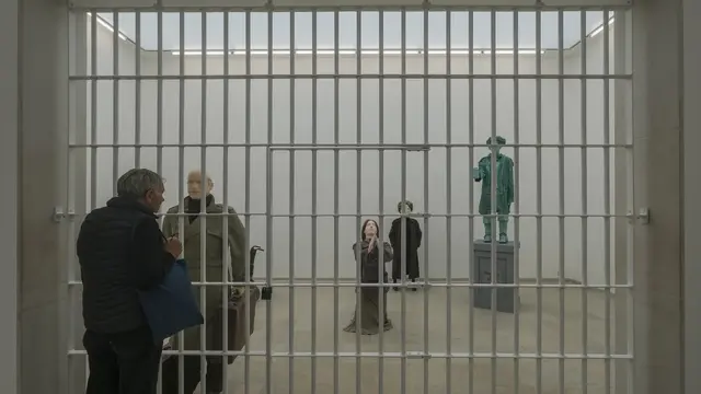 مجسمه انسانهای مختلف پشت میله‌های زندان