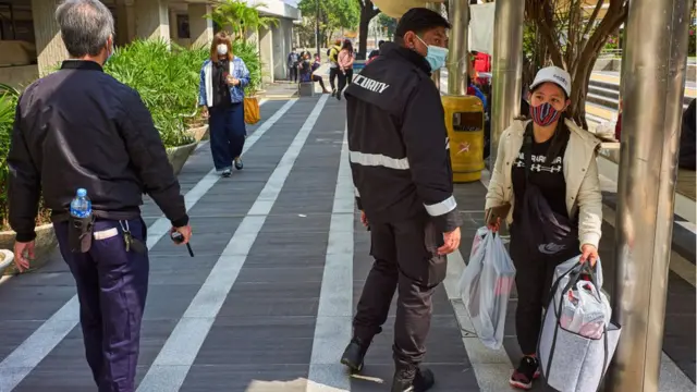 2022/02/27: Security agents tell a domestic helper who does not respect social distancing rules to leave the Central district of Hong Kong.