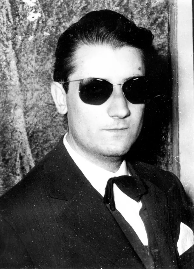 Crno-bela fotografija Branka Miljkovića u odelu sa leptir mašnom i naočarima za sunce