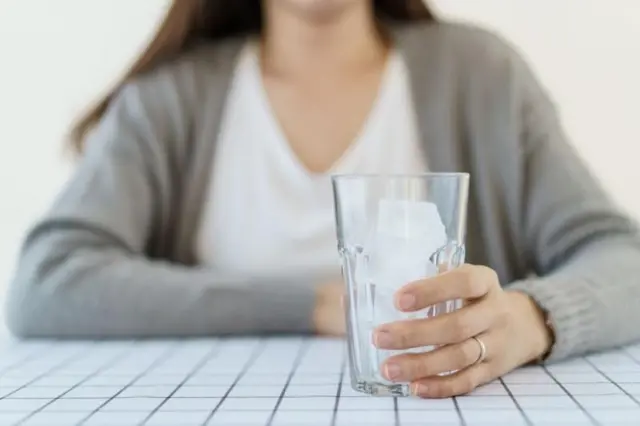 በብርጭቆ በረዶ የያዘች ሴት