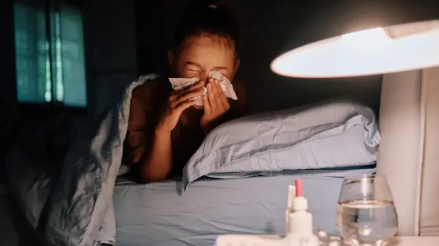 Больная в постели сморкается в платок