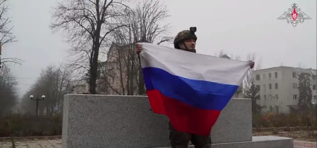 Российский военный с флагом у памятника Шевченко в Покровске.