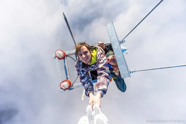 Два человека находятся на вершине металлической конструкции, фото сделано с помощью селфи-палки