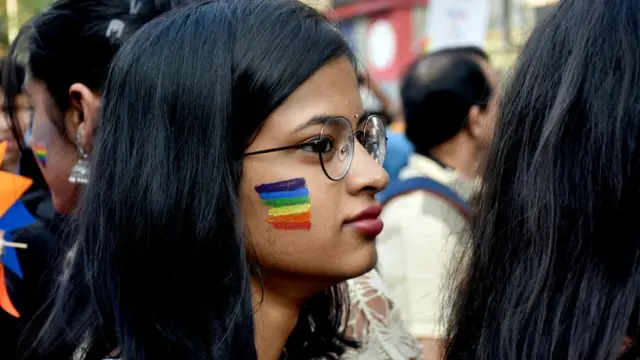 गालावर प्राईड फ्लॅग रंगवलेली तरुणी