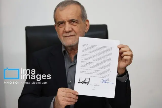 الرئيس الإيراني مسعود بزشكيان يُظهر للكاميرا ورقة من مذكرة التفاهم التي وقعها للاتفاق بين طهران وواشنطن 