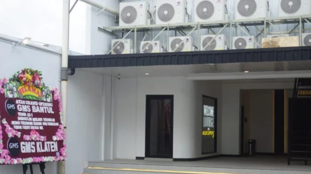 Suasana di gedung GMS, tampak ada bangunan lain dan karangan bunga di depannya. 