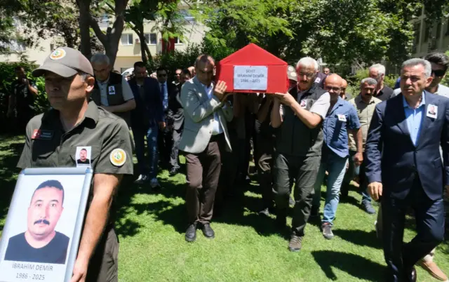 Ödemiş yangınına müdahale ederken hayatını kaybeden orman işçisi için cenaze töreni düzenlendi, Türk bayrağına sarılı tabut taşınıyor.