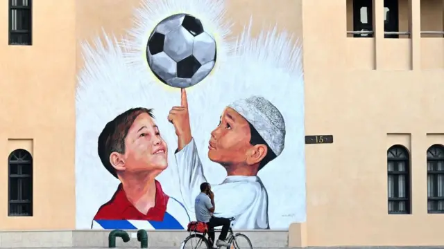 Um mural mostrando duas crianças e uma bolafutebol no Catar