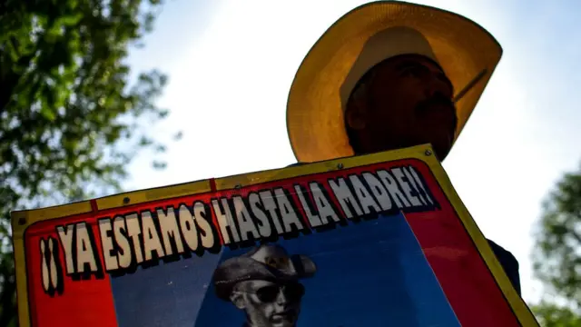 Manifestante en México con cartel de "Ya estamos hasta la madre" exige al gobierno respuestas sobre el paradero de desaparecidos.