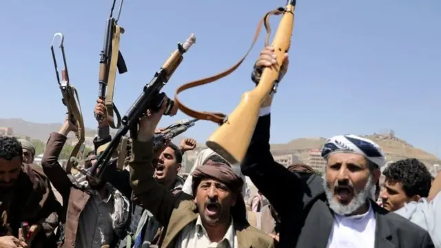 Houthi rebels raise their guns as they await food supplies in Sanaa, 21 September 2019