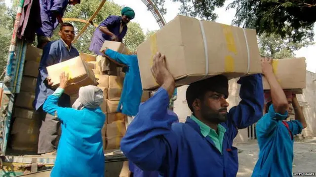 Indian porters unload boxes of dry fruits from Pakistani trucks at The Wagah Border Post
