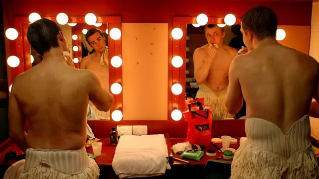 Артисты в костюмах лебедей перед зеркалом в гримуборной 