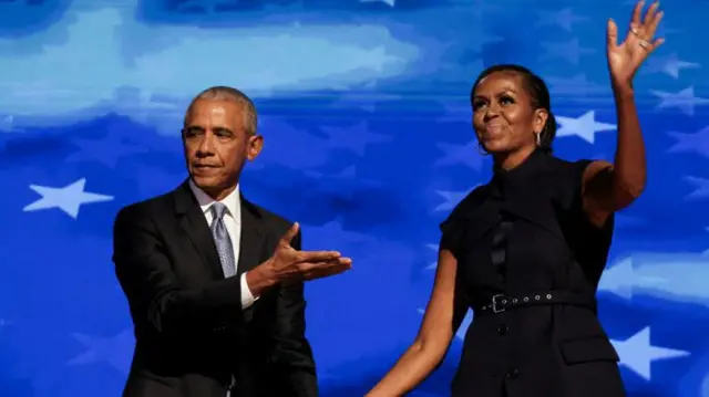 Barack Obama e Michelle Obama acenam em palco