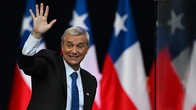 José Antonio Kast saluda a sus seguidores antes del balotaje del 14 de diciembre en que fue electo presidente de Chile, con banderas del país de fondo.