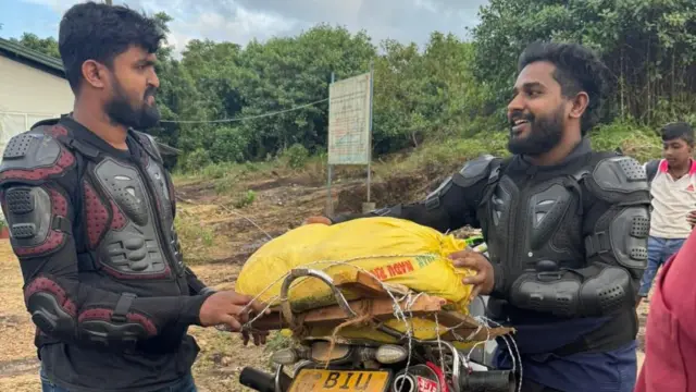  සුජේන්ද්‍ර නිරෝෂණ ඇතුළු තවත් අයෙක් යතුරුපැදියට අත්‍යවශ්‍ය භාණ්ඩ අසුරමින් සිටියි.