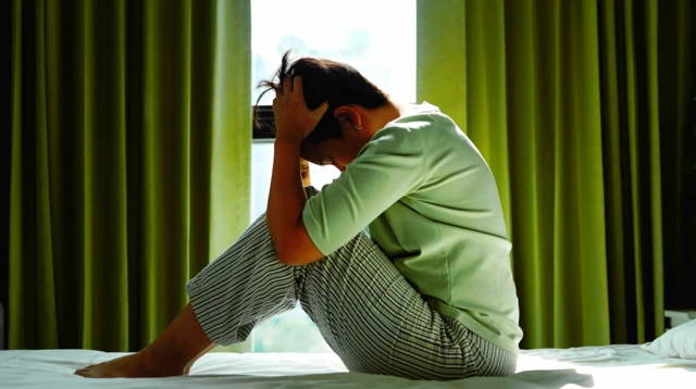 침대 위에서 머리를 감싸 안으며 고민을 하고 있다.