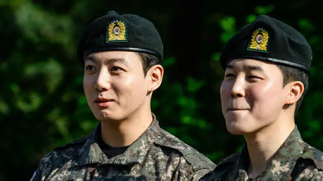 İki yeşil bereli Güney Koreli uzağa tebessüm ederek bakıyor.