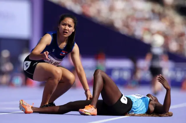 Atleta do Laos ajuda colega deitada no chão