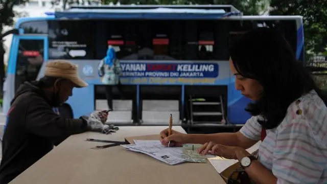 Sejumlah warga mengisi berkas pembayaran pajak kendaraan bermotor di gerai pelayanan Samsat keliling di Lapangan Banteng, Jakarta, Kamis (5/12/2024).