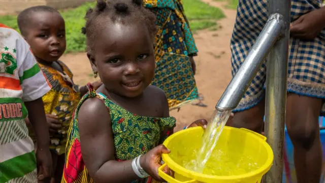 Enfants africains recueillant de l'eau d'un puits avec une pompe, Bafing, Yo, Côte d'Ivoire