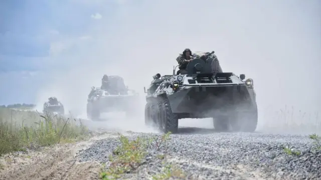 Йўлни чангитиб бораётган уч танк, тепасида ҳарбийларнинг бошлари кўринади