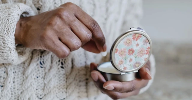 Bir siyah kadın eli, bir ilaç kutusundan bir hap çıkarıyor.