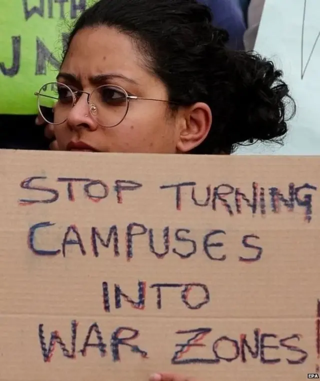 నిరసన ప్రదర్శనలో ప్లకార్డు పట్టుకున్న యువతి