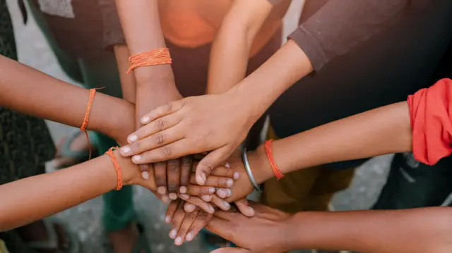 صورة تظهر مجموعة متنوعة من الأطفال يضعون أيديهم معًا رمزًا للوحدة والعمل الجماعي.