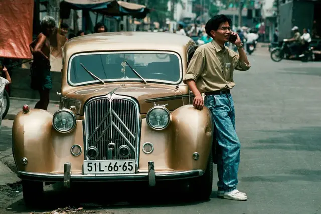Một doanh nhân trong ngành dệt may gọi điện thoại di động bên chiếc xe hơi
