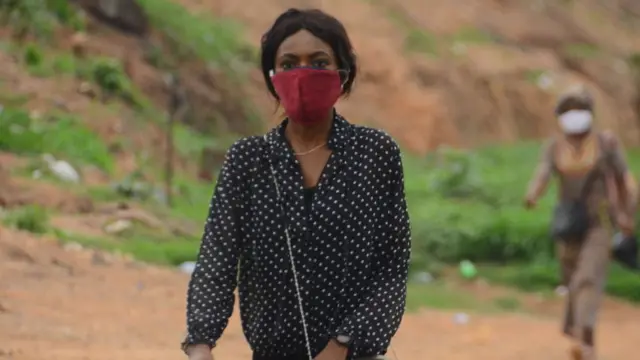 Woman dey waka with facemask