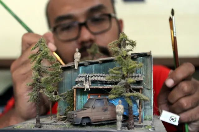 Seorang seniman sedang membuat diorama mobil bekas.