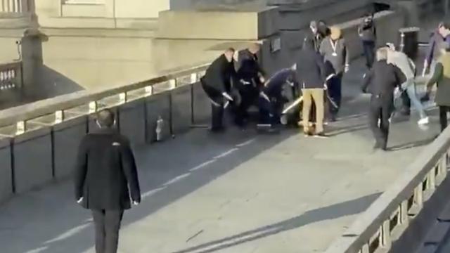 人们在伦敦桥上把一人按倒在地上