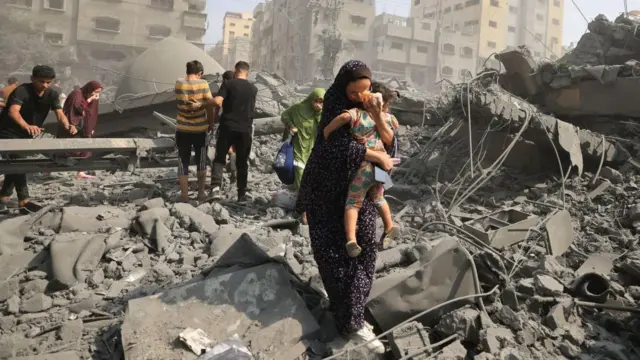 Sejumlah orang Palestina berupaya menjauh dari reruntuhan bangunan menyusul serangan udara Israel terhadap masjid Sousi di Kota Gaza, Oktober 2023.