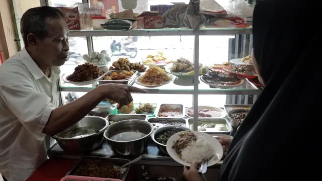 Seorang konsumen datang memesan hidangan di warteg milik Tarsih Irdayanti