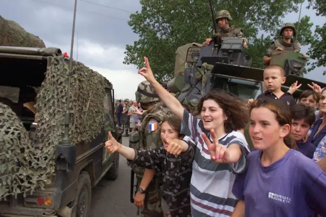 Arnavut mülteciler Kosova'daki Mitrovica'ya NATO günü kapsamında giren Fransız askerleri selamlıyor