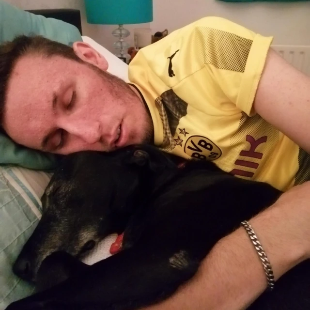 Bredli leži zatvorenih očiju, u žutoj majici, sa njegovim vernim psom Busterom