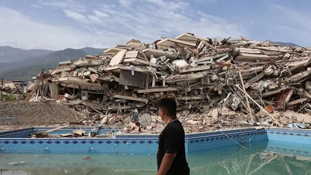 Una mujer pasa frente a una montaña de escombros tras el colapso de un edificio en el estado de La Guaira, uno de los más afectados por los terremotos en Venezuela.