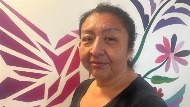 Noemí Cruz posa frente a un mural floral con una camiseta negra
