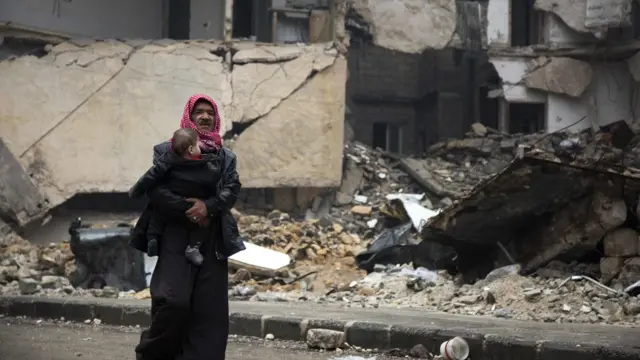 Kucağında bebek taşıyan Suriyeli bir adam