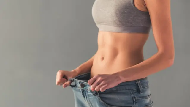 Una mujer delgada con un pantalón demasiado grande para ella